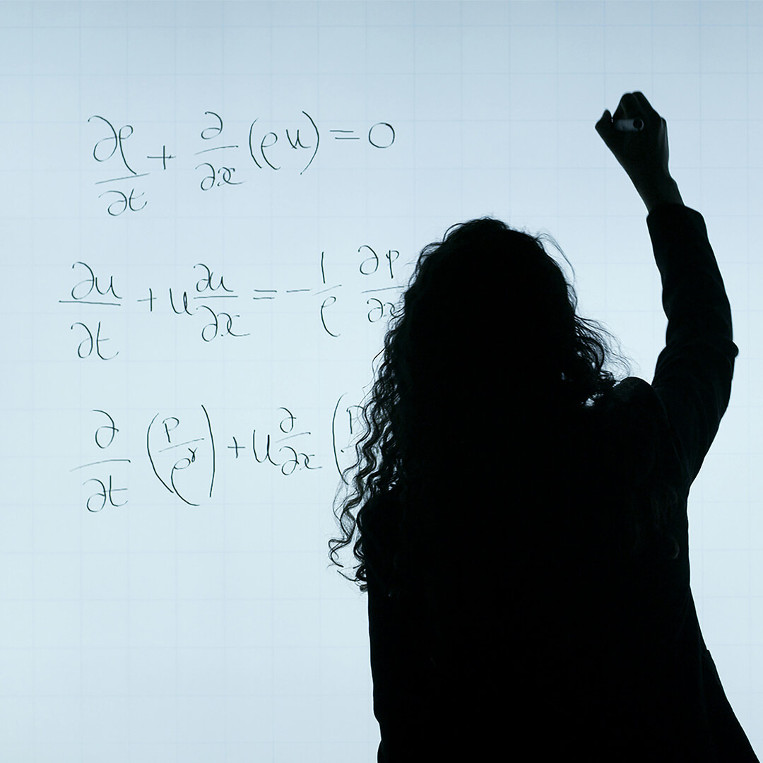Teacher writing a sum on a whiteboard.