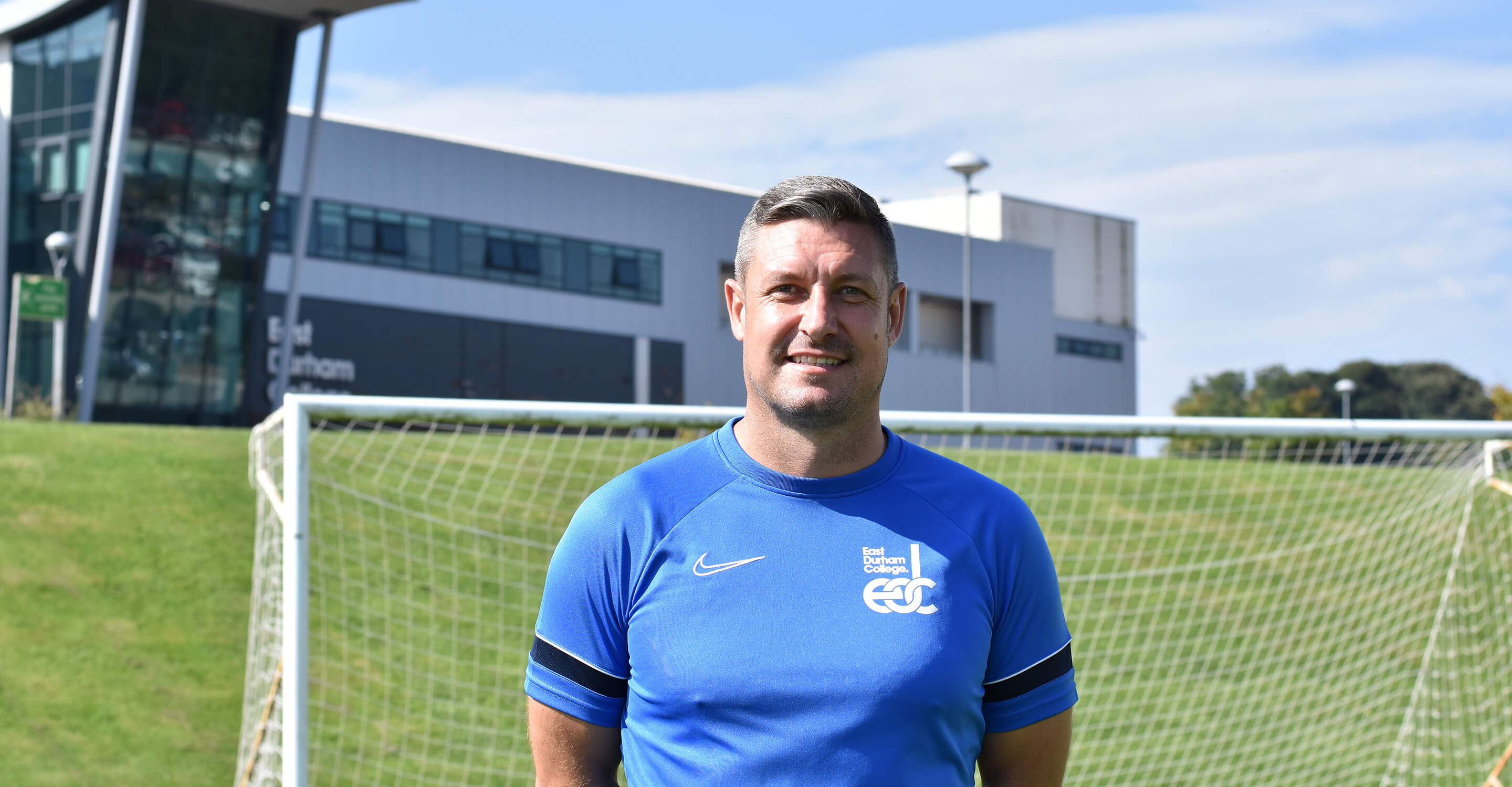 Darren Holloway stood in front of a football goal and EDC building