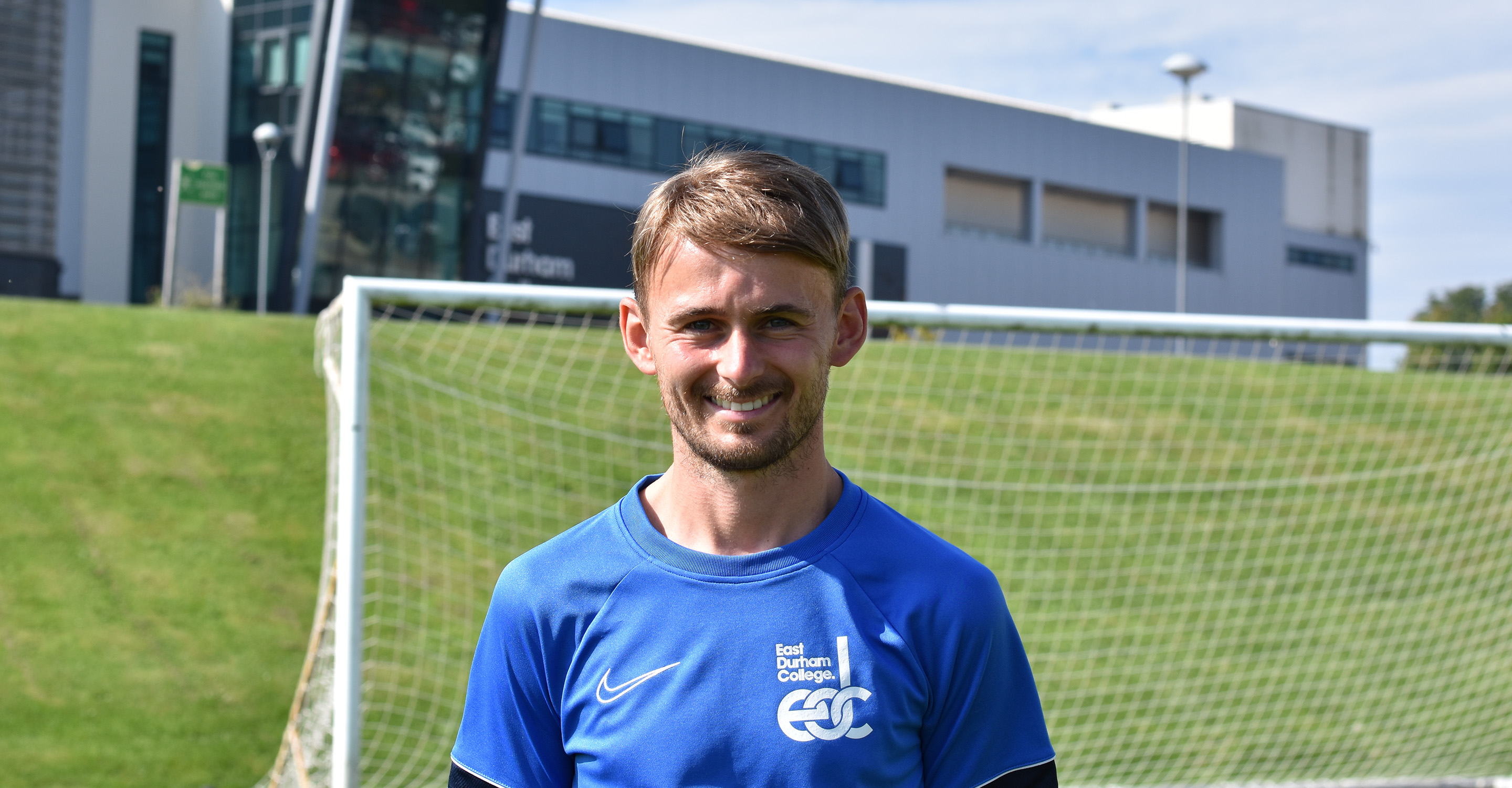 Jack Slatcher standing in front of goal and East Durham College building